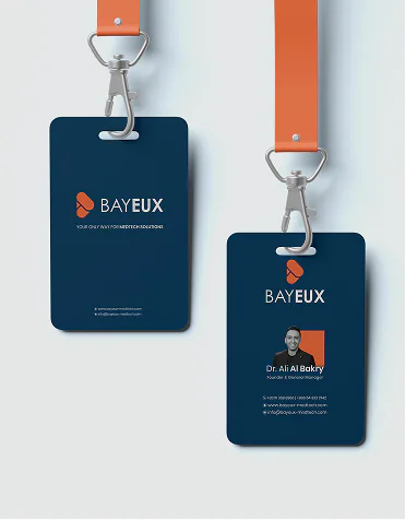 Bayeux ID badges on orange lanyards, one carrying Dr. Ali Al Bakry's card