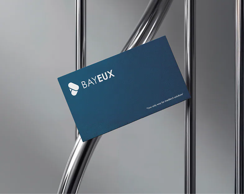 A navy Bayeux business card with the wordmark and tagline on a chrome rail