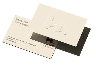 Human Care business cards, front and back, on a dark surface