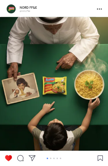 Indomie post: a grandfather and a grandson reaching for the same bowl of noodles beside an old family photo