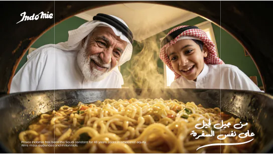 Indomie visual: a grandfather and his grandson leaning over a pan of noodles, one generation to the next