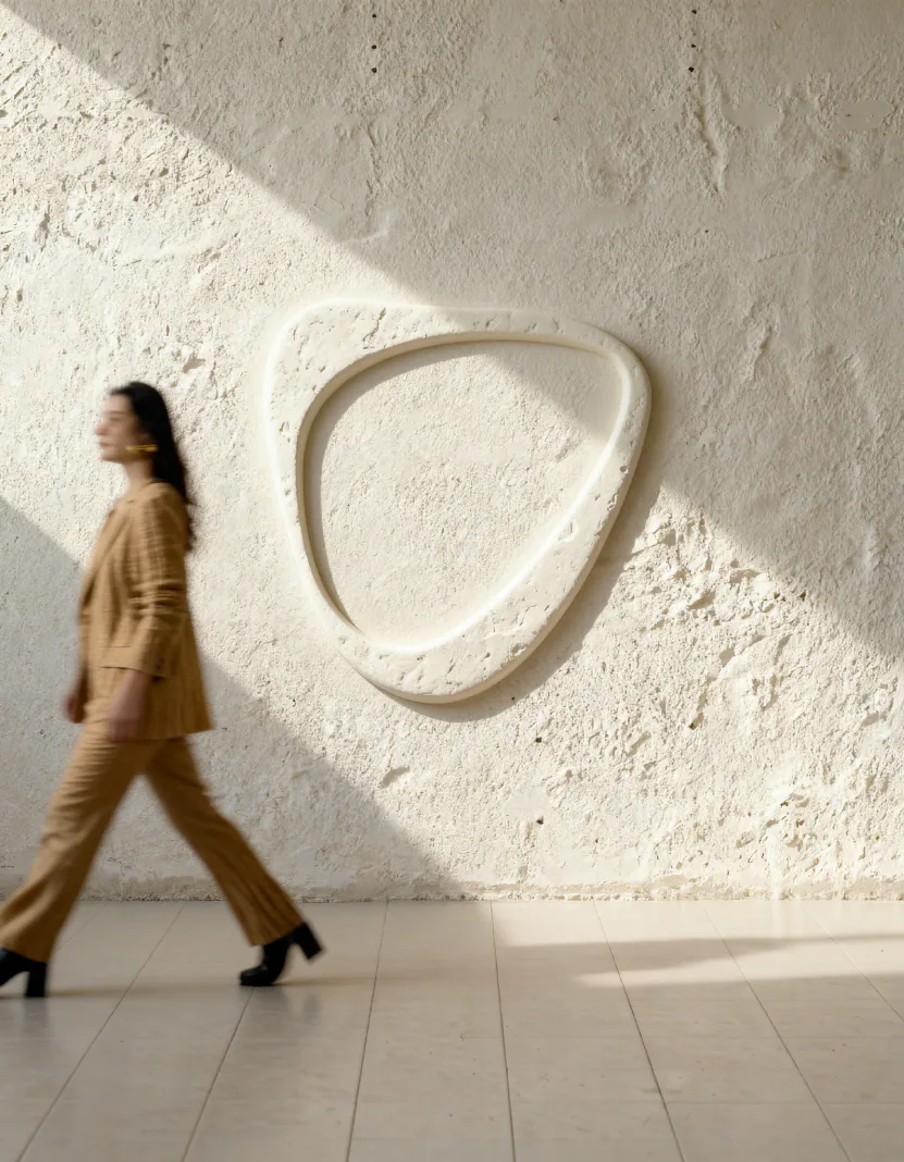 A figure in a tan suit walking past the Nord mark cut into a sunlit plaster wall